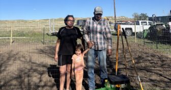 Family standing in a newly planted garden during the Medicine Root Gardening Program on the Pine Ridge Reservation