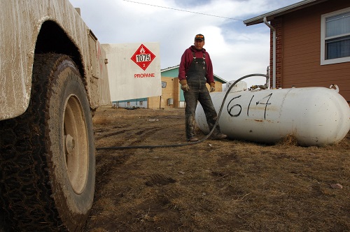 Man refilling propane tank outside home