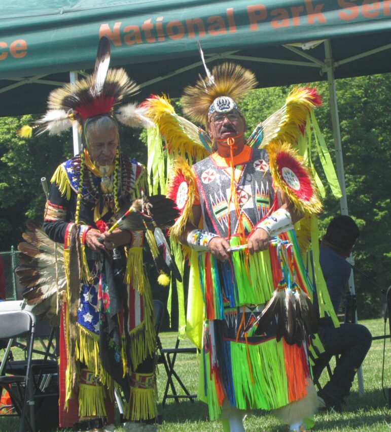 Two Native American men wearing brightly colored traditional powwow regalia at a Running Strong event.