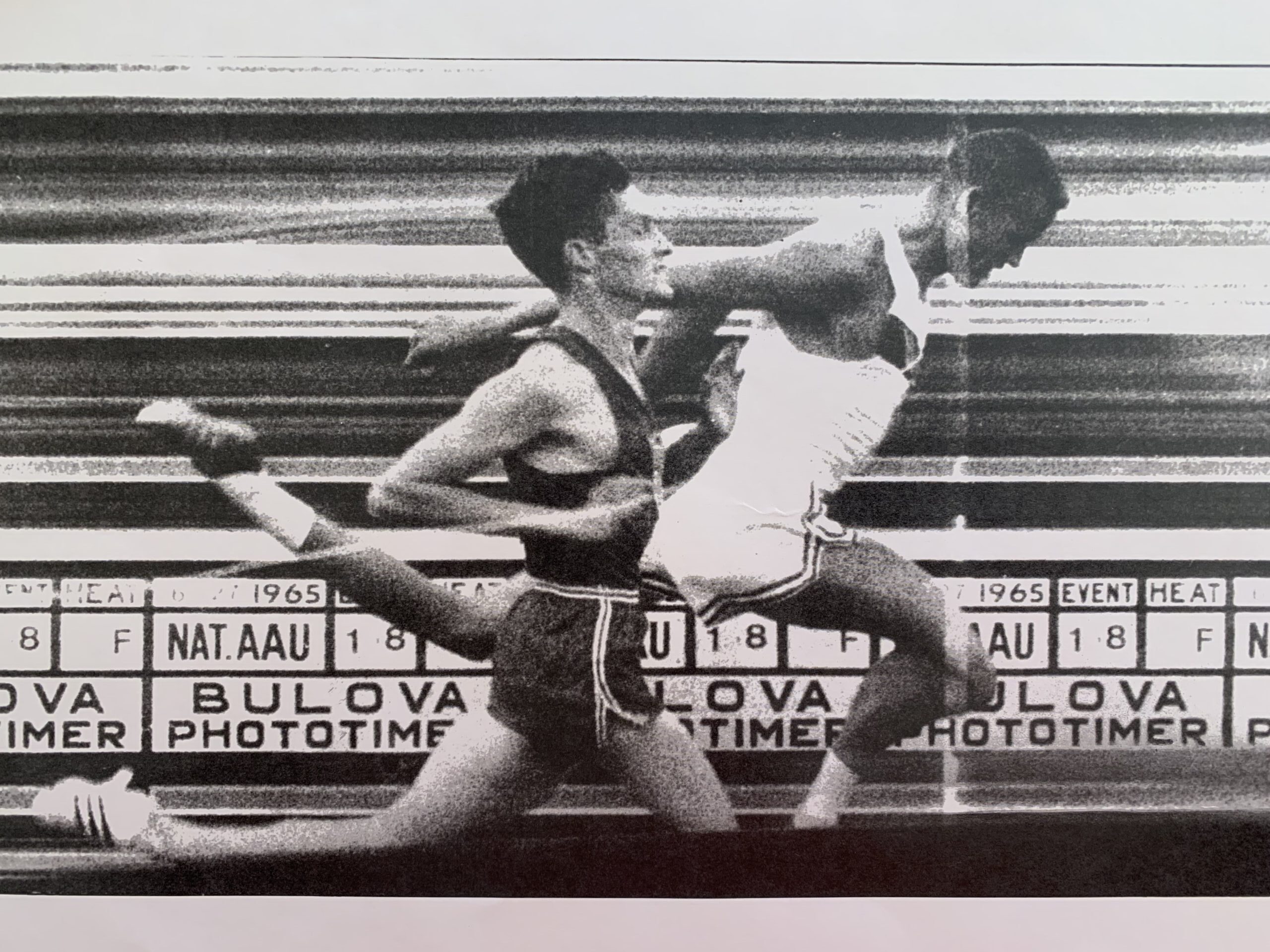Billy Mills (USA 722) crosses the finish line with arms raised, winning the 10,000m gold medal at the 1964 Tokyo Olympics.