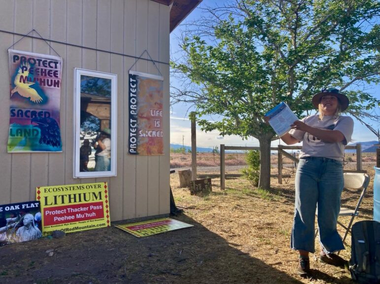 An organizer speaks at the event, standing by signs protesting the Thacker Pass (Peehee Mu’huh) lithium mine.