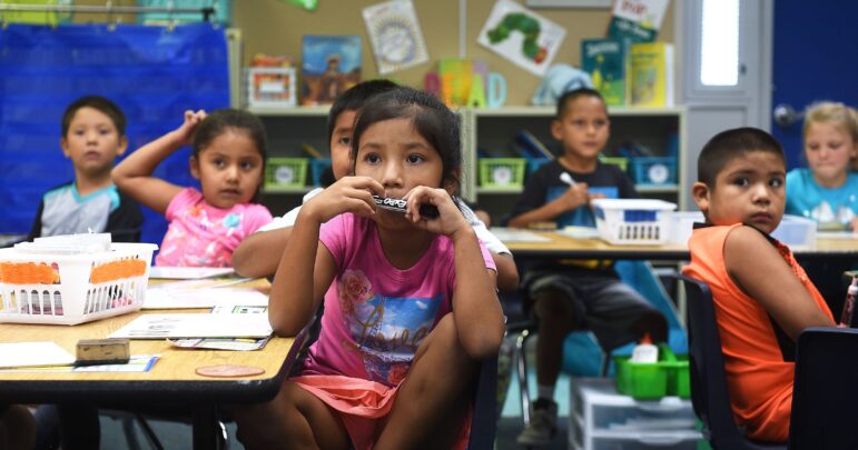 Young Native students sit attentively at their desks in a classroom, participating in an education program.