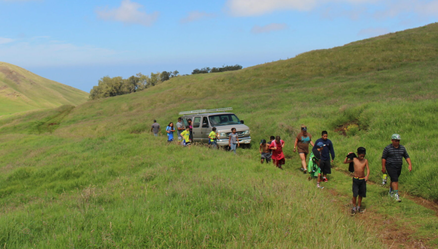 Native youth and adults walk on ancestral lands, part of a Landback and Indigenous land stewardship program.