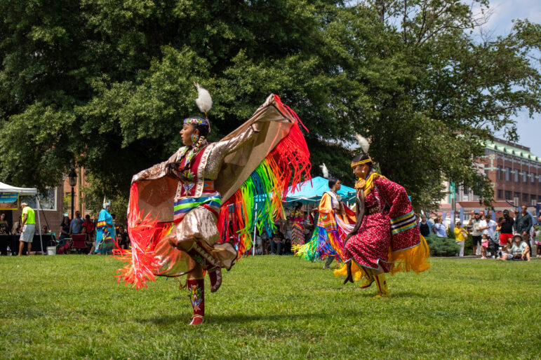Native American women in vibrant, traditional regalia dancing at a cultural event, part of a culture revitalization program.