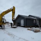 An excavator next to a home with solar panels, installing sustainable tech for a tribal energy sovereignty project.
