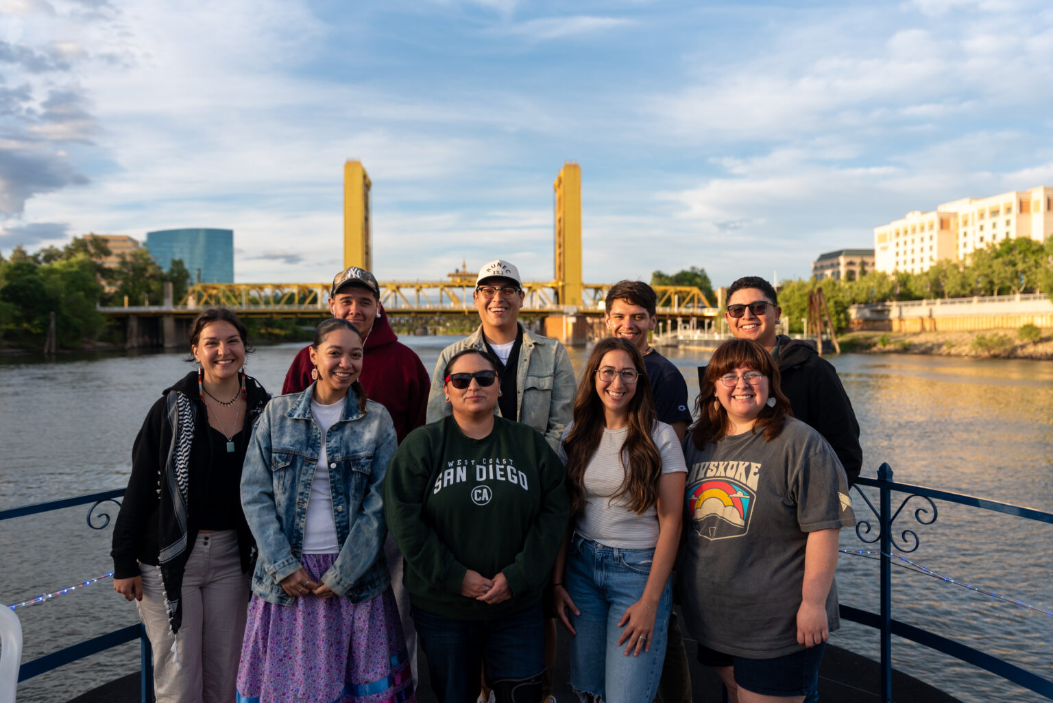 9 Native youth gathered together in front of the Sacramento Bridge