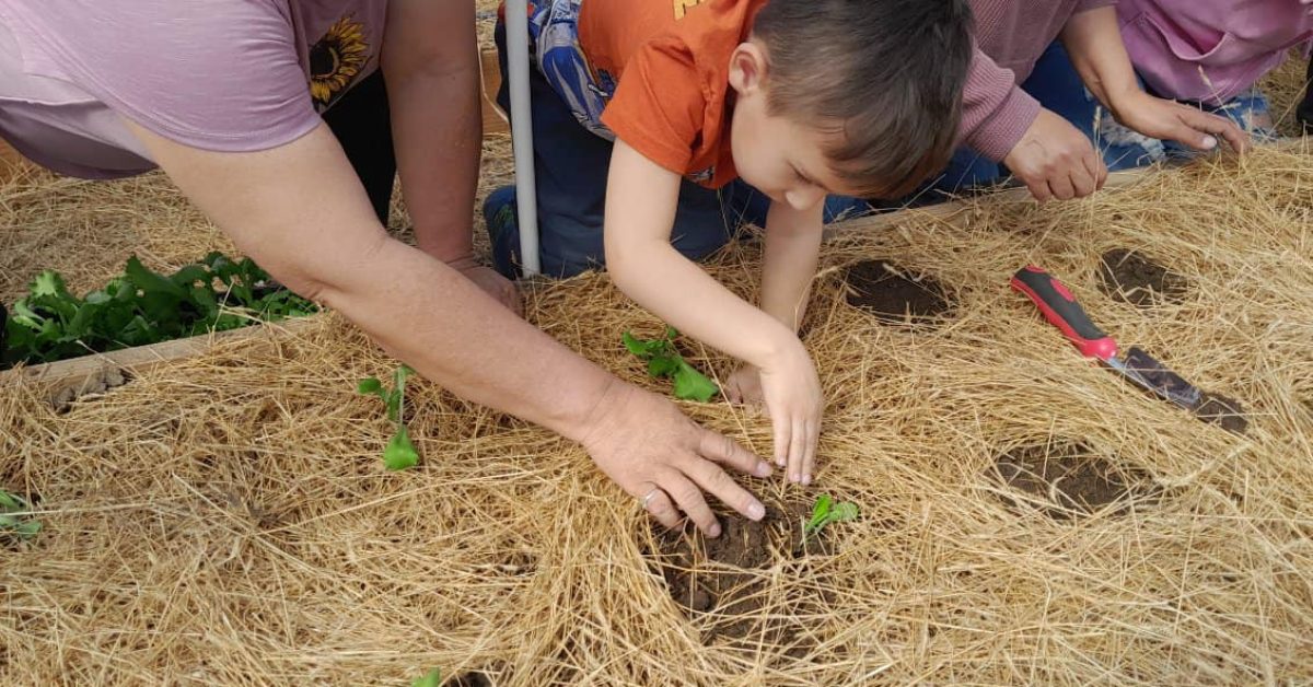A Native American woman is helping a young boy learn how to plant crops in an effort to transform Native American food deserts.