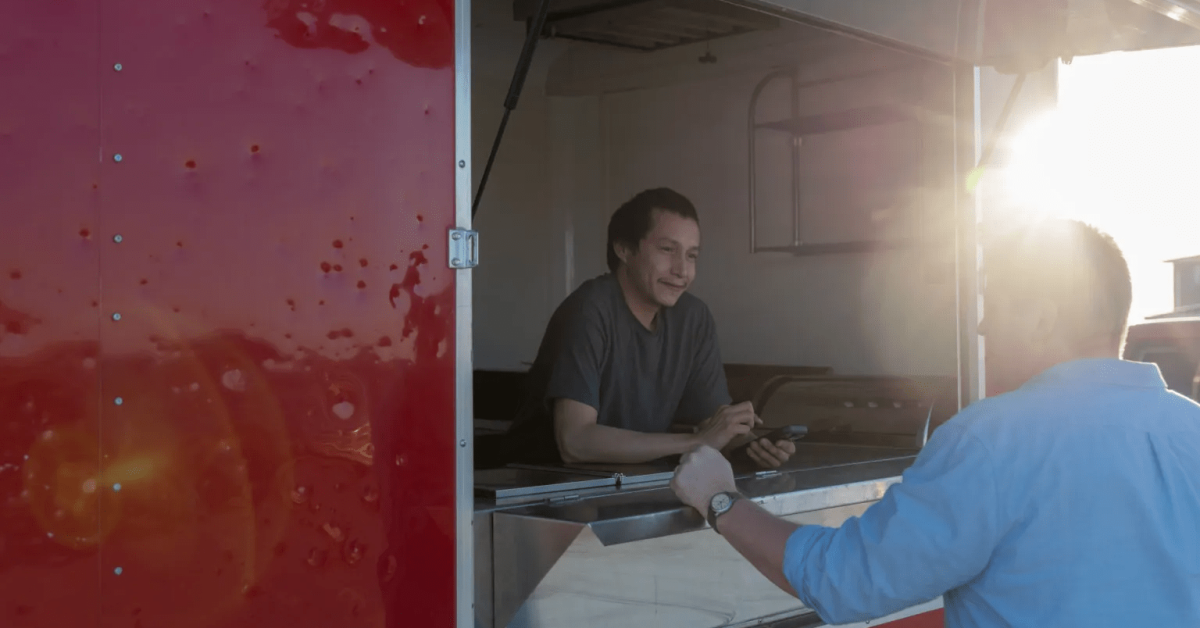A Native entrepreneur serving a customer from his food truck, symbolizing community-driven business and economic sovereignty in Indian Country.